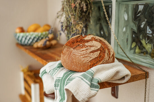 A home-baked fresh loaf of bread on a wooden shelf. Whole grain spelt bread