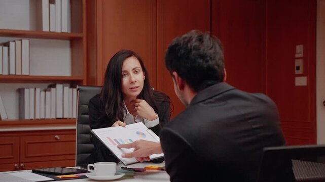 Business professionals discussing financial information and reviewing a report together during a corporate meeting in a professional office.
