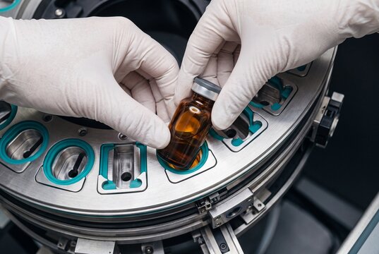 Laboratory Technician Placing Amber Medicine Vial into Automated Packaging Machine