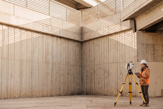 Female Civil Engineer Using a 3D Laser Scanner and Digital Tablet to Inspect Concrete Infrastructure at a Construction Site