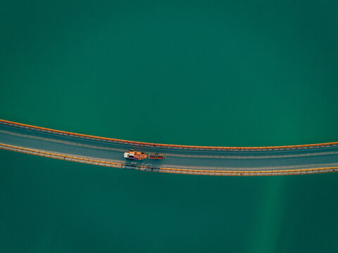 Aerial view of a bridge crossing the turquoise waters of Lago Castreccioni with a vehicle driving across the structure in Cingoli, Marche, Italy.