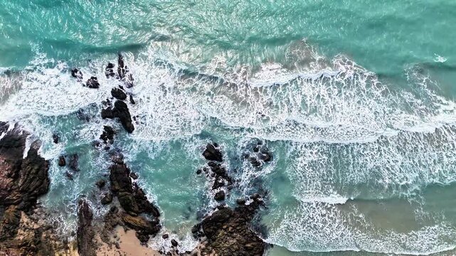 aerial view of metamorphic rock formations along coastal shoreline with ocean waves revealing natural geological textures and earth structures