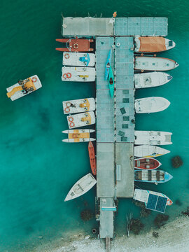 Aerial view of Lago Castreccioni with various small boats and kayaks moored at a wooden pier in the turquoise water of Cingoli, Marche, Italy.
