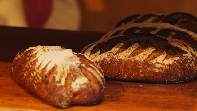 Freshly baked rye sourdough loaves with scored patterns on wooden tray. Delicious organic bakery products cool down in craft workshop