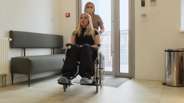 Doctor helps disabled patient reach reception area. Physician escorts woman through hallway toward reception counter in private clinic. Slow motion