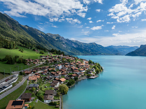 Aerial view of the village of Oberried am Brienzersee along turquoise Lake Brienz, with traditional houses and historic railway station, Oberried am Brienzersee, Canton of Bern, Switzerland.