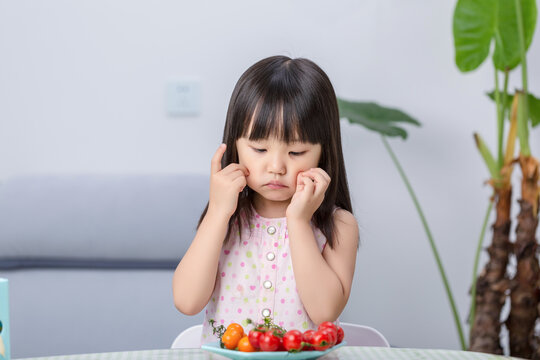 Unhappy Asian little girl refusing to eat vegetables, picky eating and child behavior concept