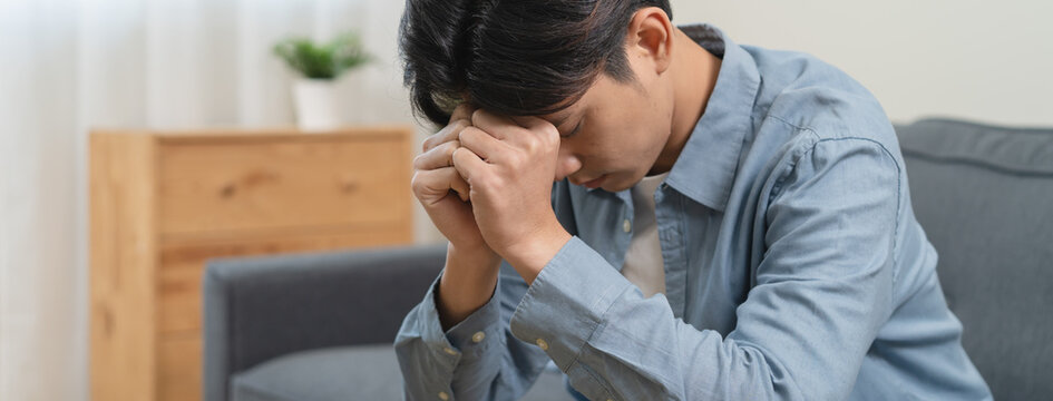 Stressed male feeling depressed and lonely on the sofa in the house.