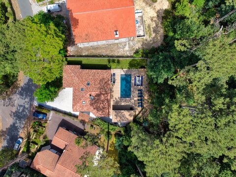 Aerial view of a villa with a swimming pool and wooden deck surrounded by dense pine forest in Hossegor, Nouvelle-Aquitaine, France.