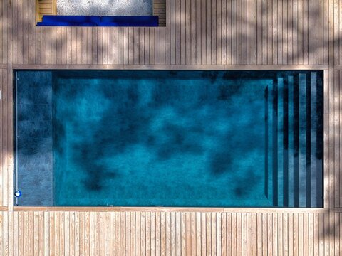 Aerial view of a rectangular swimming pool with deep blue water and wooden decking in Hossegor, Nouvelle-Aquitaine, France.