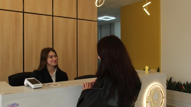Well-dressed woman approaches elegant reception desk in private clinic. Female registers for upcoming medical examination. Slow motion