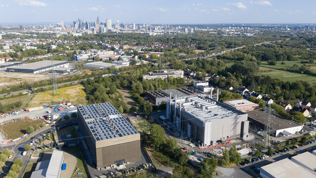 Aerial view of large industrial warehouses and commercial buildings with the Frankfurt skyline visible in the distance, Frankfurt am Main, Hessen, Germany.
