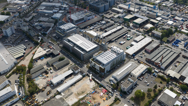 Aerial view of modern office buildings, warehouses, and industrial facilities situated in an urban district with parking lots in Frankfurt am Main, Hessen, Germany.