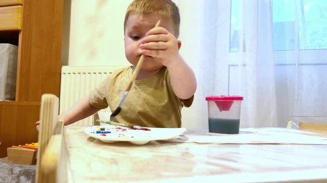 Child mixing watercolors with fingers on paper. Tactile learning about color blending. Sensory play strengthens neural connections. Art therapy and artistic development