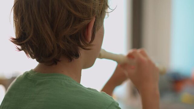 A little boy learns to play the flute at home, practicing with focus and enthusiasm in a cozy, warm setting. A charming scene of early musical exploration, creativity, and childhood growth.