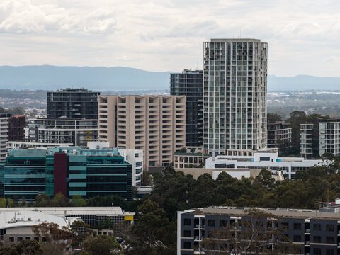 Aerial view of modern high-rise apartment buildings and office blocks forming a dense suburban skyline in a mixed-use precinct in Norwest, New South Wales, Australia.
