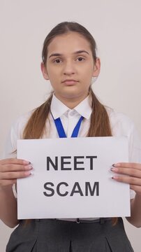 Vertical Shot of Indian Schoolgirl Standing with NEET SCAM Poster