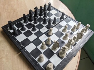 A high angle view of a plastic chess board with pieces set up for a game. © Maslan