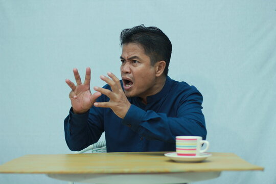 Angry adult man gesturing with both hands and shouting, expressing frustration and strong emotion.