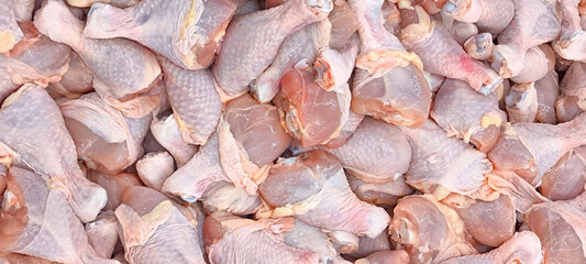Large quantities of raw chicken legs with the skin still attached. These fresh chicken legs are prepared for wholesale or retail sale. © Pisan