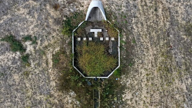 Aerial view of an abandoned and overgrown concrete spillway structure surrounded by dry prairie landscape in Johnstown, Colorado, United States.