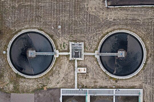 Aerial view of a wastewater treatment plant featuring two large circular settling tanks with central walkways and industrial infrastructure in Erie, Colorado, United States.