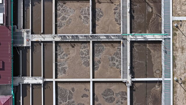 Aerial view of the aeration tanks at a wastewater treatment plant with bubbling water and concrete walkways in Erie, Colorado, United States.