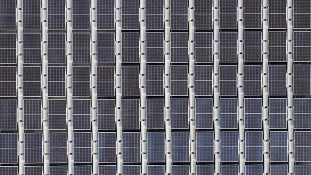Aerial view of a large solar farm with rows of photovoltaic panels arranged in a grid pattern in Erie, Colorado, United States.