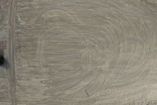 Aerial view of intricate tire tracks and circular patterns on a barren dirt field in Erie, Colorado, United States.