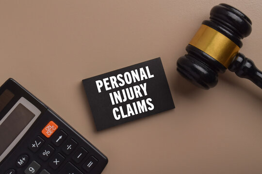 Gavel, calculator, and a card labeled personal injury claims representing legal proceedings, compensation, insurance disputes, financial assessment, and personal injury law.