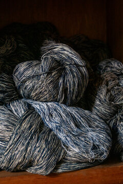 Twisted skeins of indigo dyed kasuri yarn piled on a dark wooden shelf, Kyushu region, Chikugo, Japan
