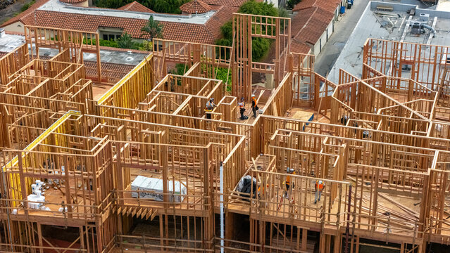 Aerial view of the wooden framing of a building under construction with workers on site in Los Angeles, California, United States.