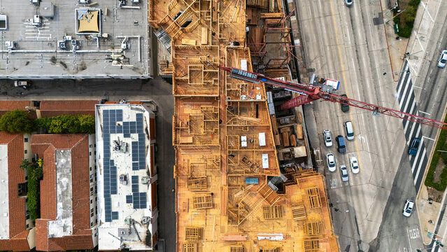 Aerial view of a construction site with wooden framing and a red crane located near an intersection in Los Angeles, California, United States.