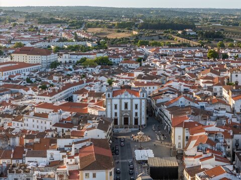 Aerial view of the Church of Santo Antao in the historic center of Evora, surrounded by traditional white buildings with terracotta rooftops in Evora, Distrito de Evora, Portugal.