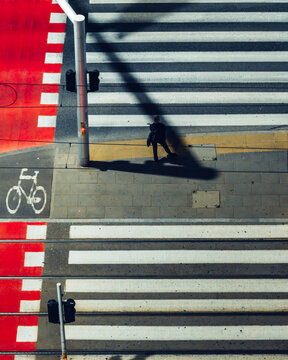 Aerial view of a pedestrian crossing with a red bike lane and tram tracks in Poland.