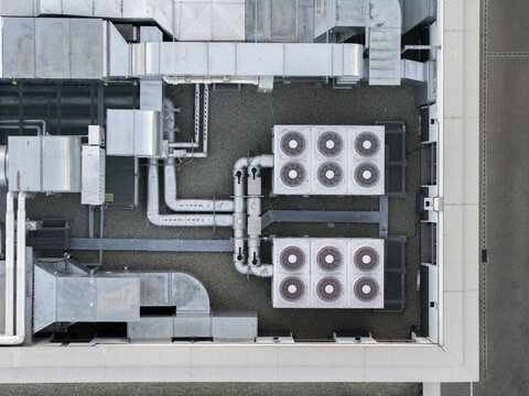 Aerial view of industrial data center rooftop featuring large HVAC cooling units, complex ventilation ductwork, and technical infrastructure, Poland.