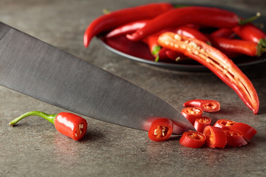 Kitchen knife and fresh red chili peppers.