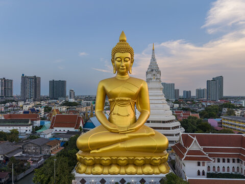 Aerial view of the giant golden Buddha statue at Wat Paknam Phasi Charoen surrounded by the urban cityscape of Bangkok, Krung Thep Maha Nakhon, Thailand.