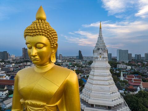 Aerial view of the large golden Buddha statue and white stupa at Wat Paknam Phasi Charoen overlooking the urban cityscape of Bangkok, Krung Thep Maha Nakhon, Thailand.