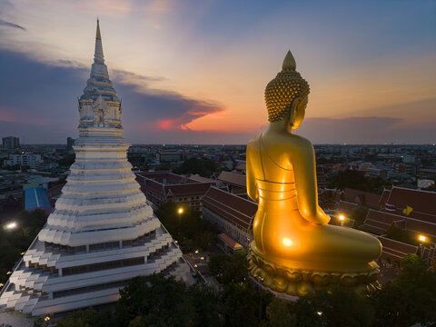 Aerial view of Wat Paknam Phasi Charoen featuring the golden Buddha statue and white stupa at sunset in Bangkok, Krung Thep Maha Nakho, Thailand.