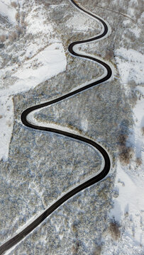 Aerial view of a winding road cutting through a snow-covered landscape in the mountains near Bejar, Castile and Leon, Spain.