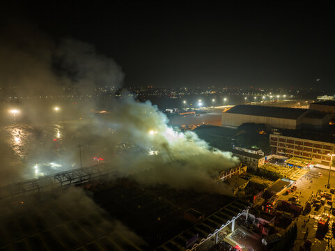 Aerial view of a large fire at an industrial facility at night with thick smoke rising and emergency vehicles responding in Dhaka, Dhaka Division, Bangladesh.