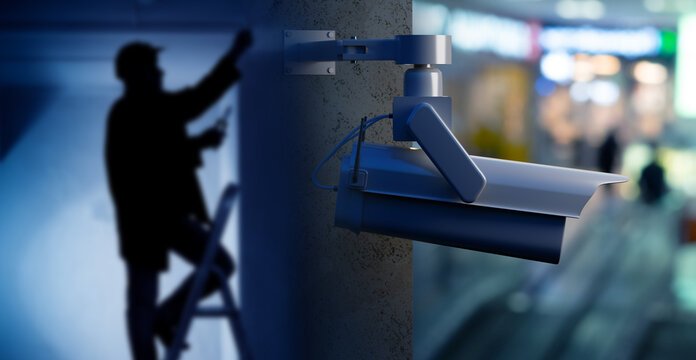 Video surveillance installation, technician installs and adjusts a security camera for monitoring, protection and control of an indoor public area.