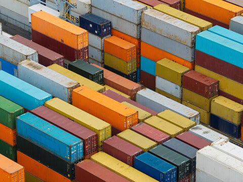 Aerial view of colorful shipping containers stacked in a busy industrial port terminal in the United Kingdom.
