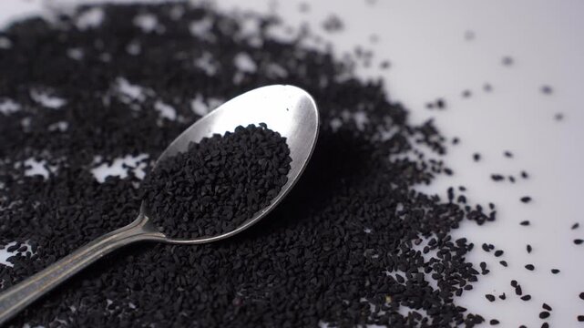 Black Cumin Seeds on Silver Spoon and White Surface - Nigella sativa
