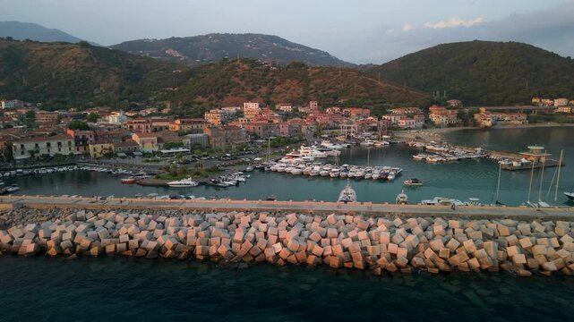 Acciaroli Cilento Italy cinematic 4K drone video. flyover along harbor and boats gaining altitude to reveal town panorama and mountains. Golden hour sunset authentic italian coastal towns hidden gems