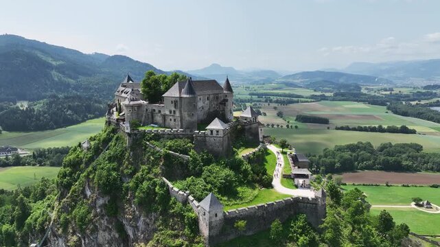 Cinematic drone footage capturing Hochosterwitz Castle on hilltop, fortified walls, dramatic cliffs, summer colors, sweeping aerial movement, historical landmark atmosphere