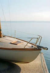 Fototapeta premium Luxury travel and leisure lifestyle, classic wooden sailboat moored at a quiet dock on calm ocean water during a peaceful summer morning