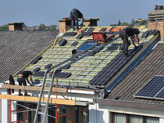Ouvriers qui rénovent la toiture d’une maison pour isolation et remplacement des tuiles © joef