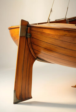 Nautical craftsmanship and maritime heritage, vintage wooden sailboat hull detail with polished timber planks and metal fittings on a clean white background